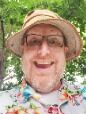 A man with glasses and a bucket hat smiles broadly at the camera.