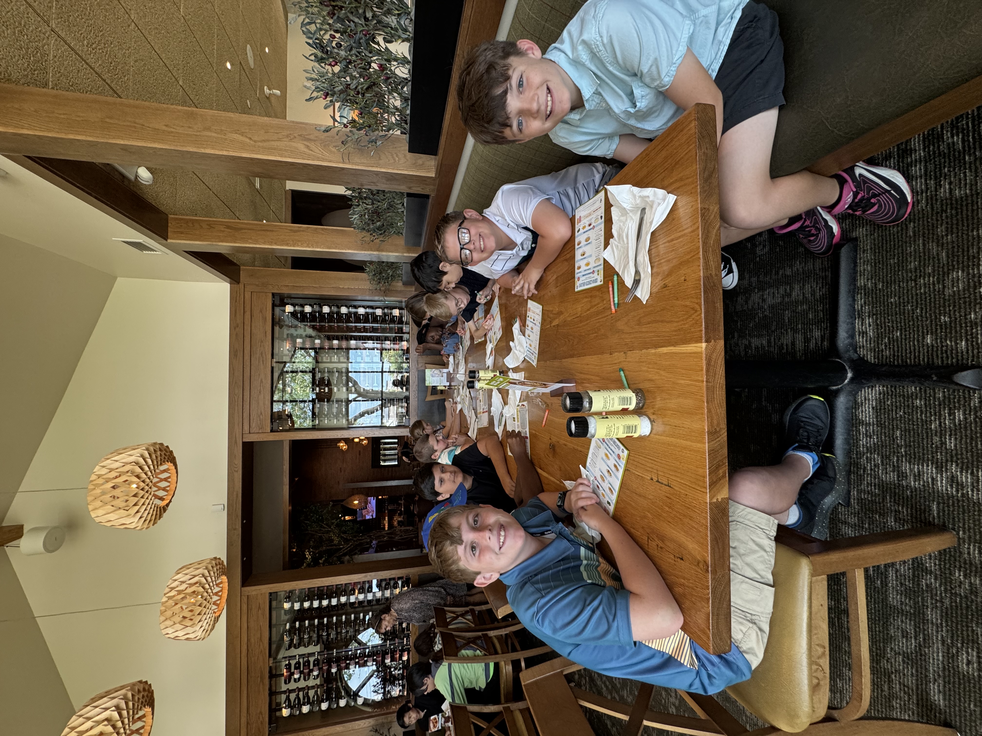 A group of boys sit at a wooden table in a restaurant, looking at menus.