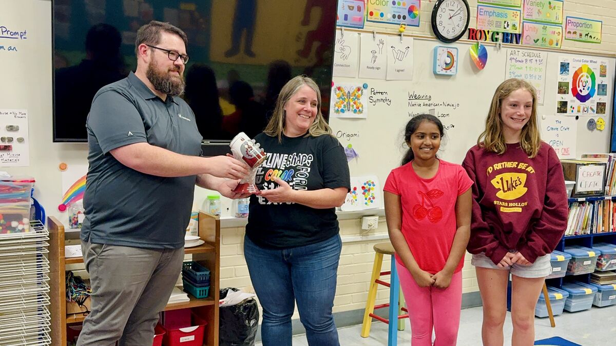 Woman accepts trophy from man with two girls looking on