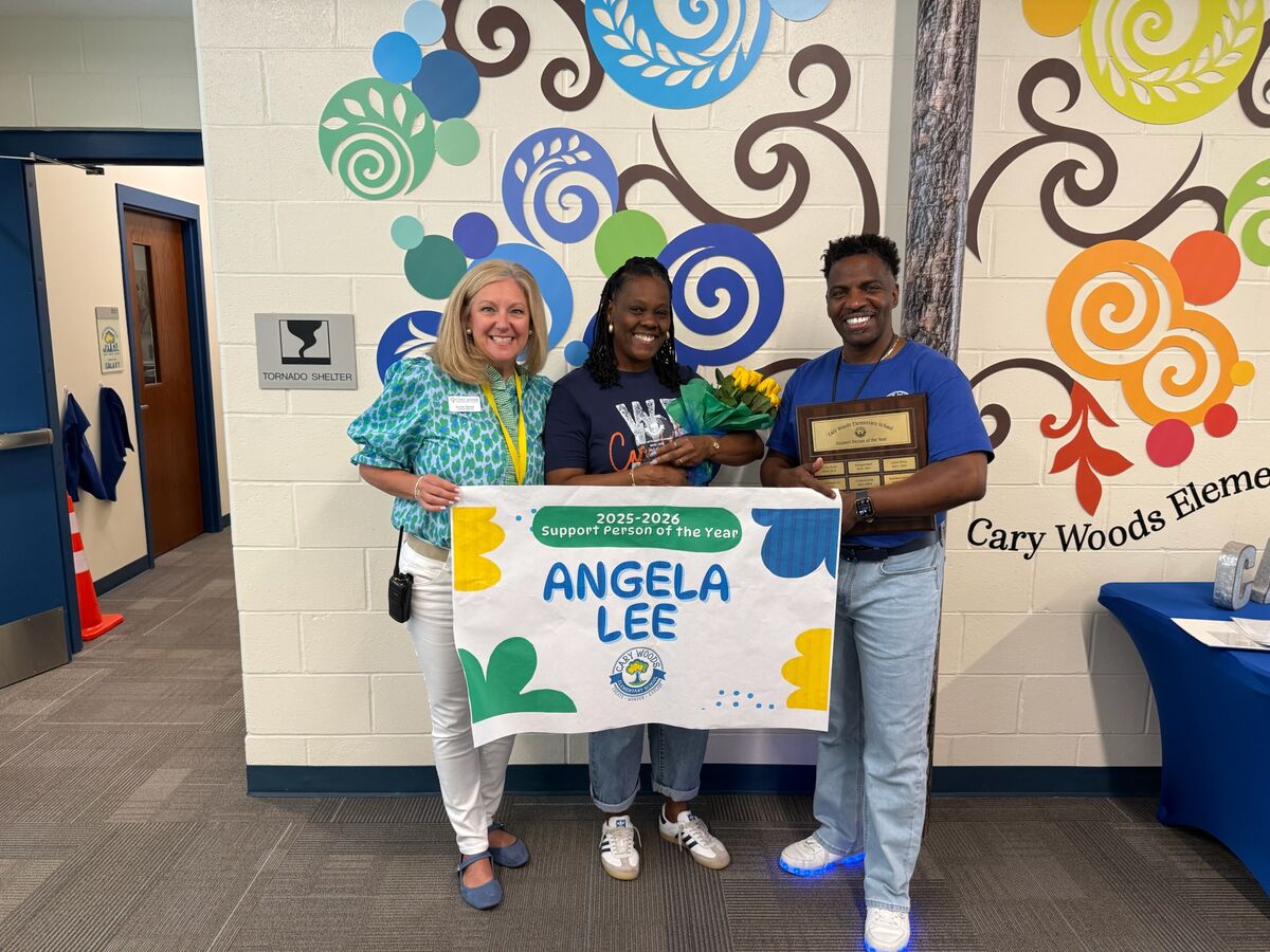 Three smiling individuals stand together, holding a banner that reads '2025-2026 Support Person of the Year ANGELA LEE'.