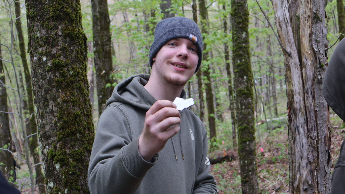 A student holds up a piece of ceramic on the annual archaeological dig in Florence, NY