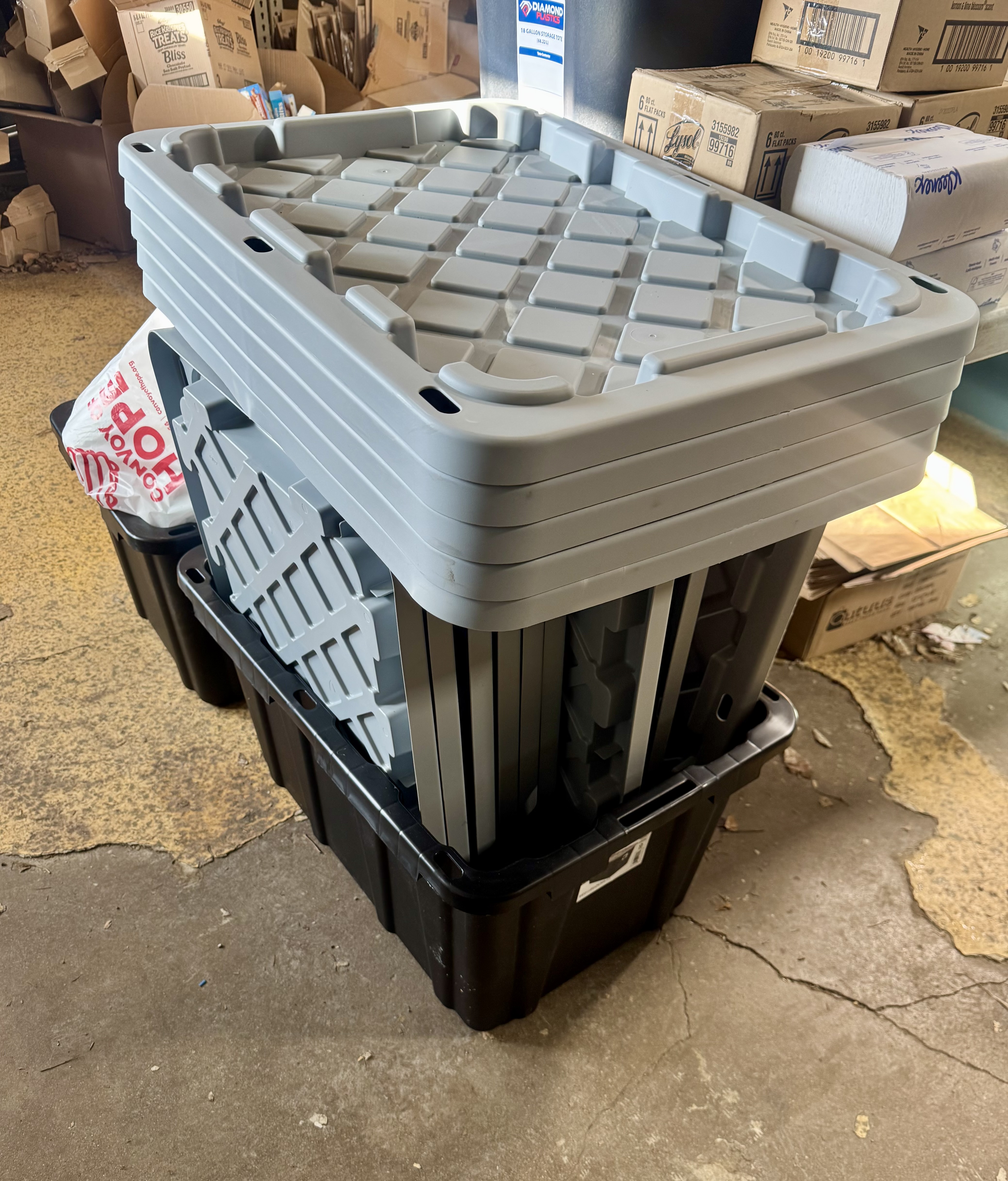 Stacked gray storage totes with textured lids sit on top of black bins.