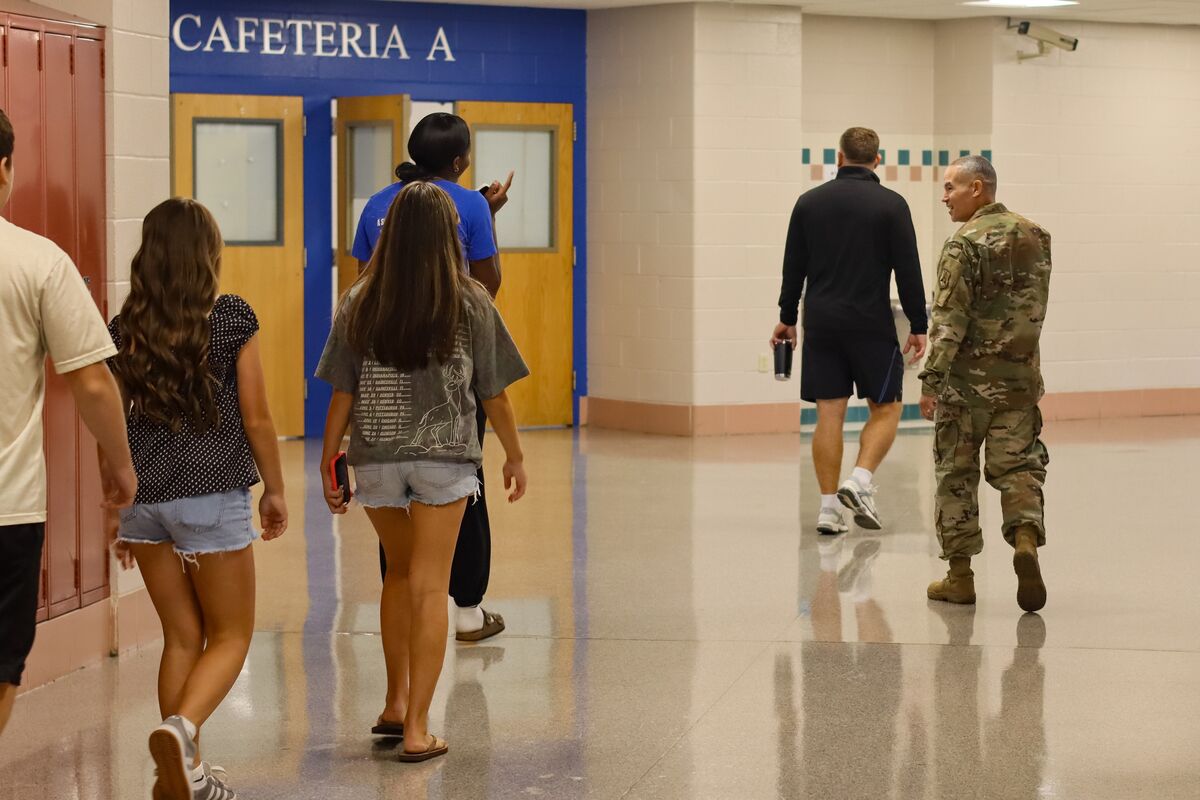 People walk down a hallway with a sign for "CAFETERIA A" above double doors.