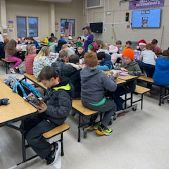 Students sit around tables in a book discussion