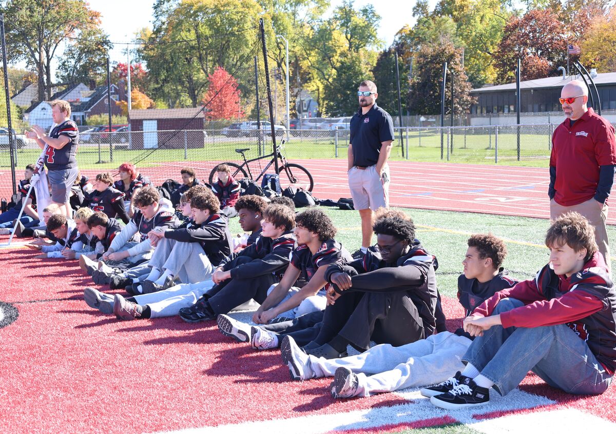A large group of students sitting in the sunny day.