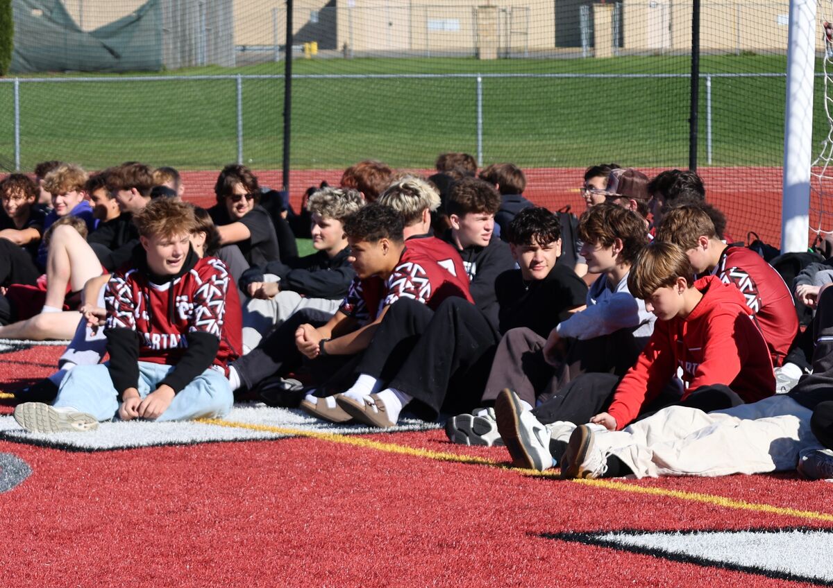 A large group of students sitting in the sunny day.