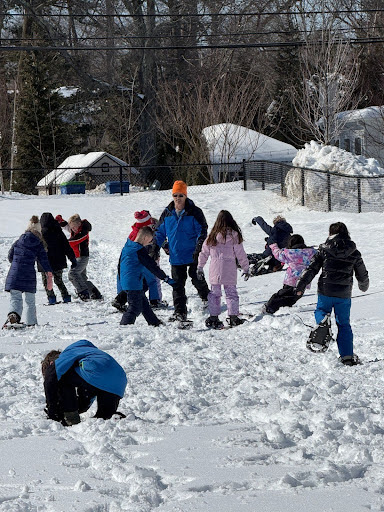 Mr. Guzzi and students snowshoeing on the field.