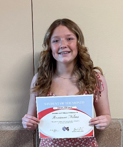 A smiling young woman holds a "Student of the Month" certificate.