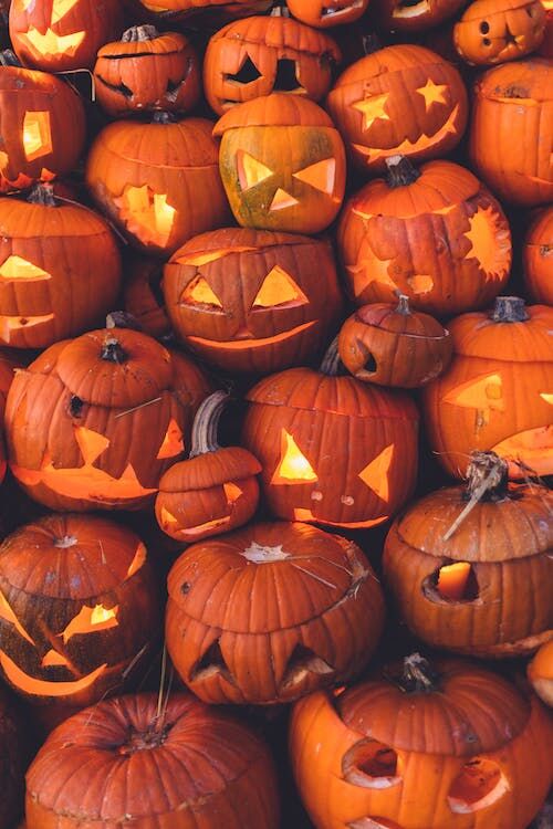 A vibrant display of numerous glowing jack-o'-lanterns stacked tightly together.