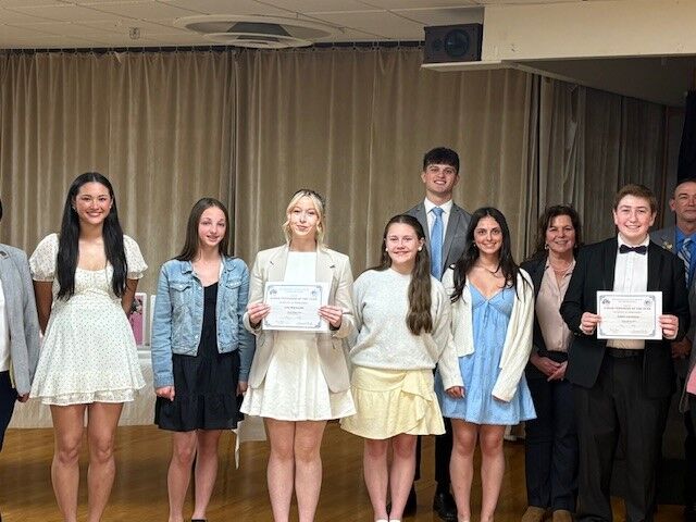 A group of young people and adults pose for a photo, some holding certificates.
