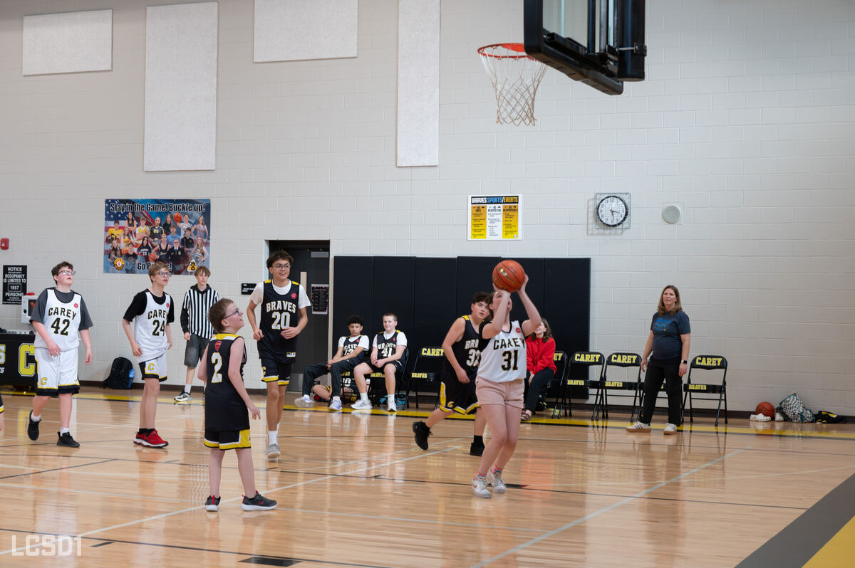 A young basketball player in a white and black jersey with the number 31 shoots a basketball during a game.