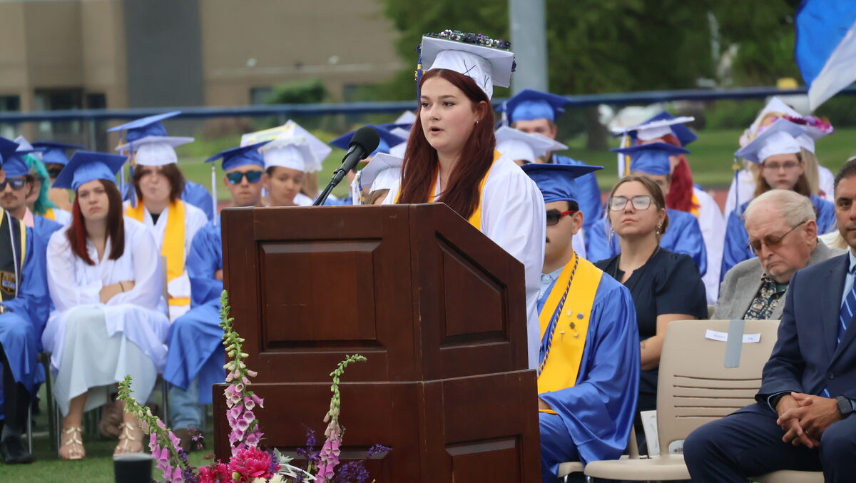 Ella Winters, in white cap and gown, gives her Valedictorian Address at the podium