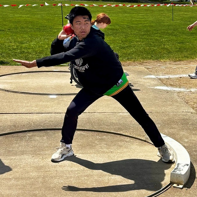 A young athlete prepares to throw a shot put during a track and field event.