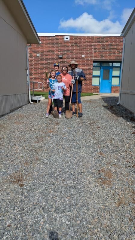 People standing with shovels in front of a building
