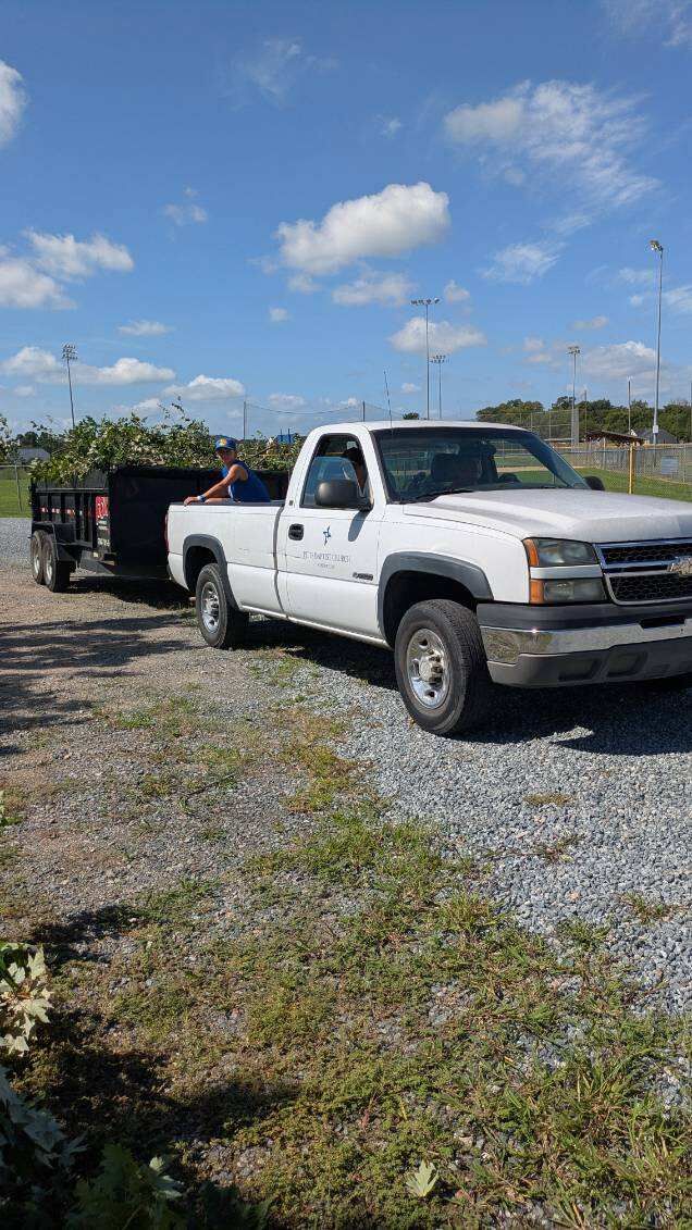 A white pickup truck hauling a trailer full of debris