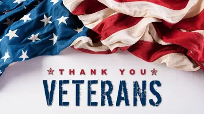 A draped American flag lies on a white surface above text that reads "THANK YOU VETERANS".