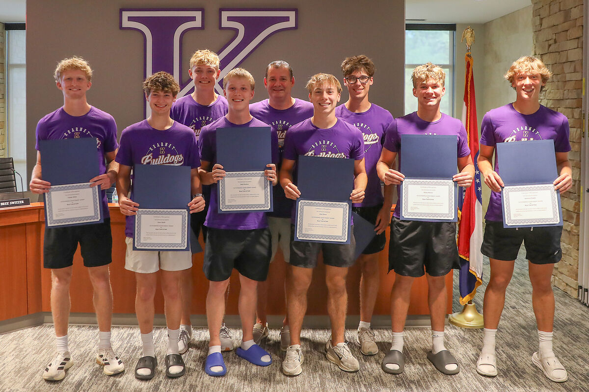 A group of young men in purple 'Kearney Bulldogs' shirts stand holding certificates.