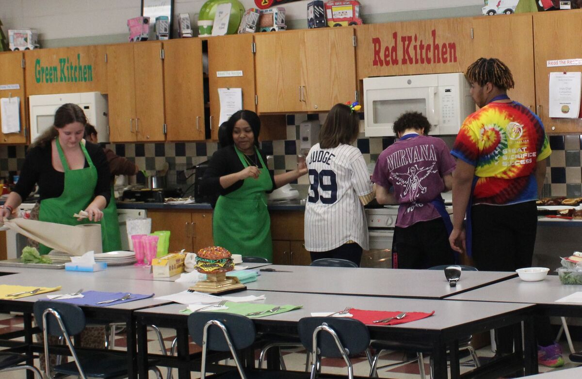 Students in a kitchen classroom, labeled 'Green Kitchen' and 'Red Kitchen', prepare food.