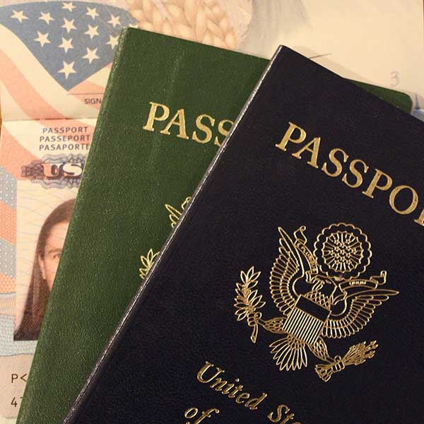 A close-up view shows a dark blue United States passport resting next to a green passport and an open document.