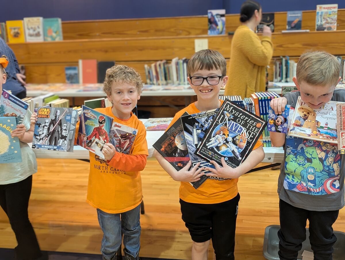 Three smiling children proudly hold stacks of books, including Star Wars, Power Rangers, and space-themed titles.