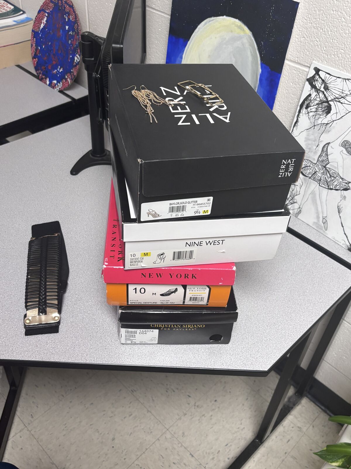 A collection of shoe boxes from brands like Nine West and Christian Siriano are stacked on a desk.