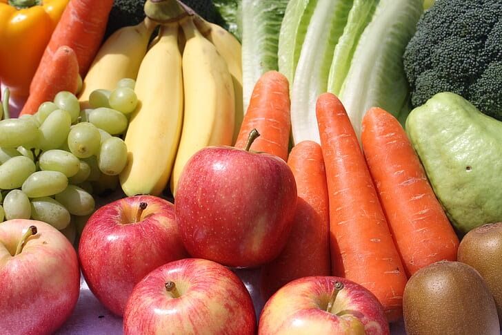A vibrant assortment of fresh fruits and vegetables, including red apples, yellow bananas, and bright carrots.