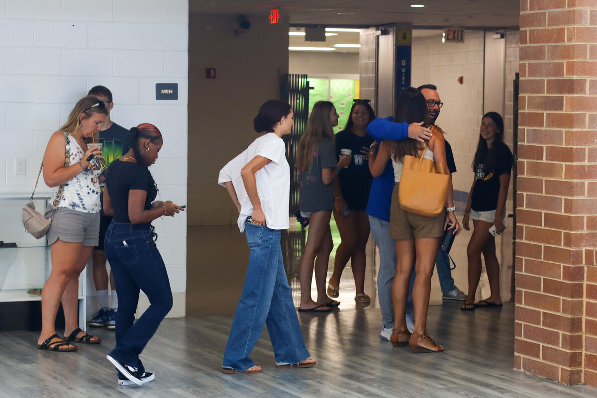 A group of young adults are gathered in a hallway, some talking and others walking.