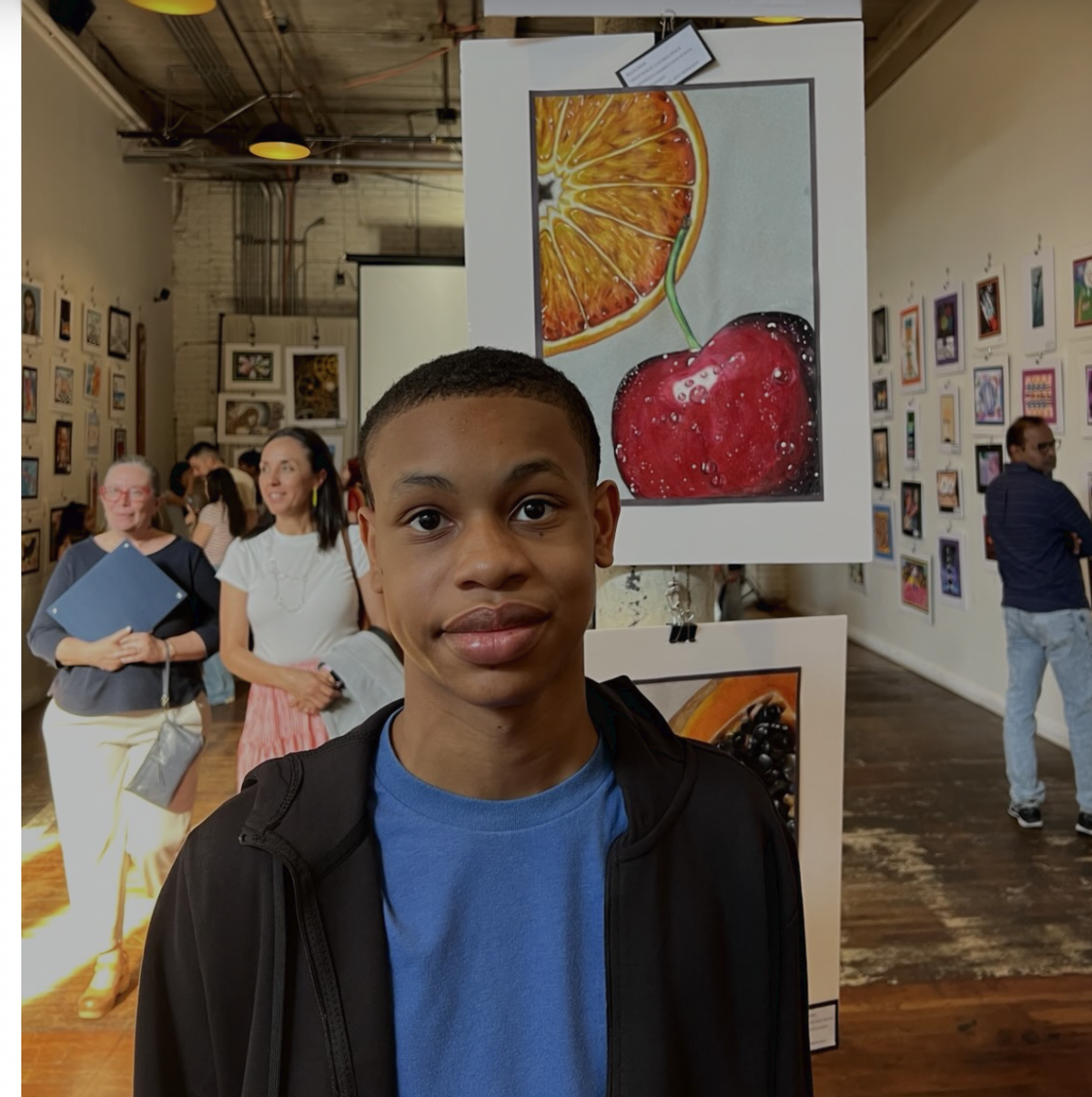 A young person stands in an art gallery, with artwork displayed on the walls.