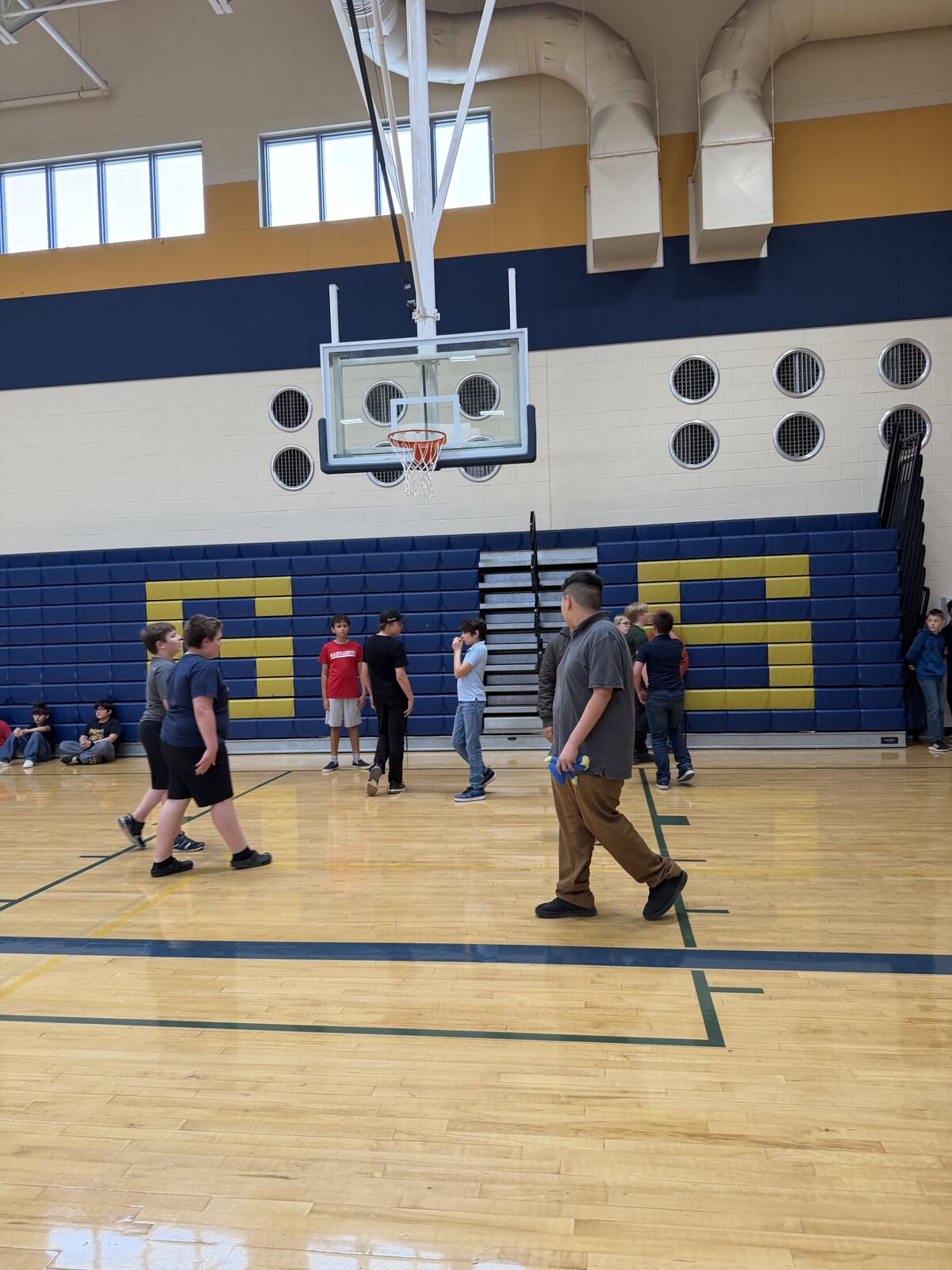 A group of young people stand on a polished wooden basketball court.