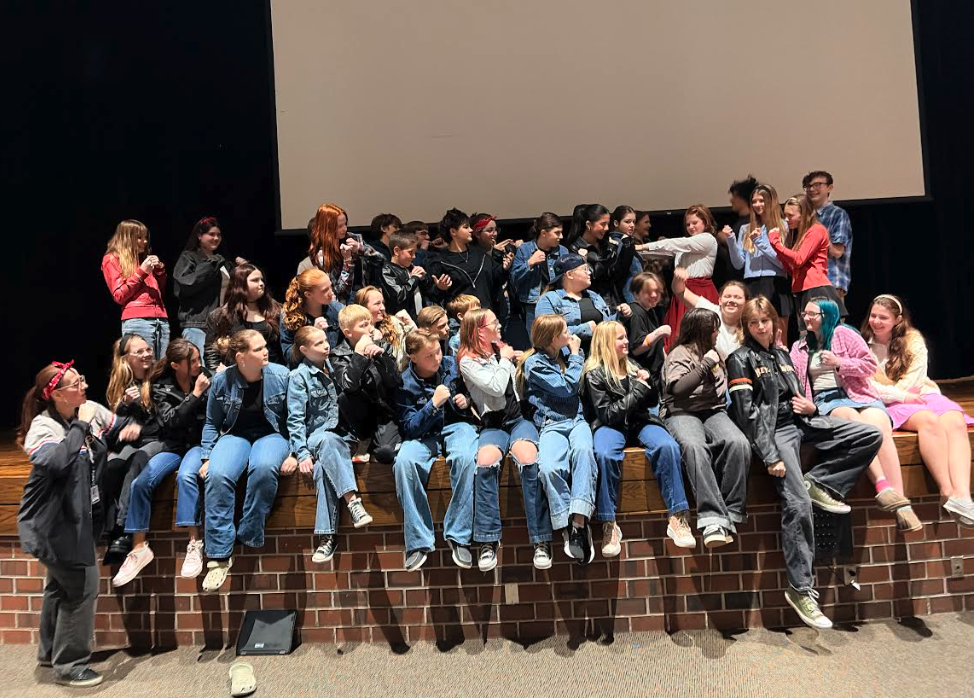 A large group of young people are seated on a raised platform, many with fists raised.