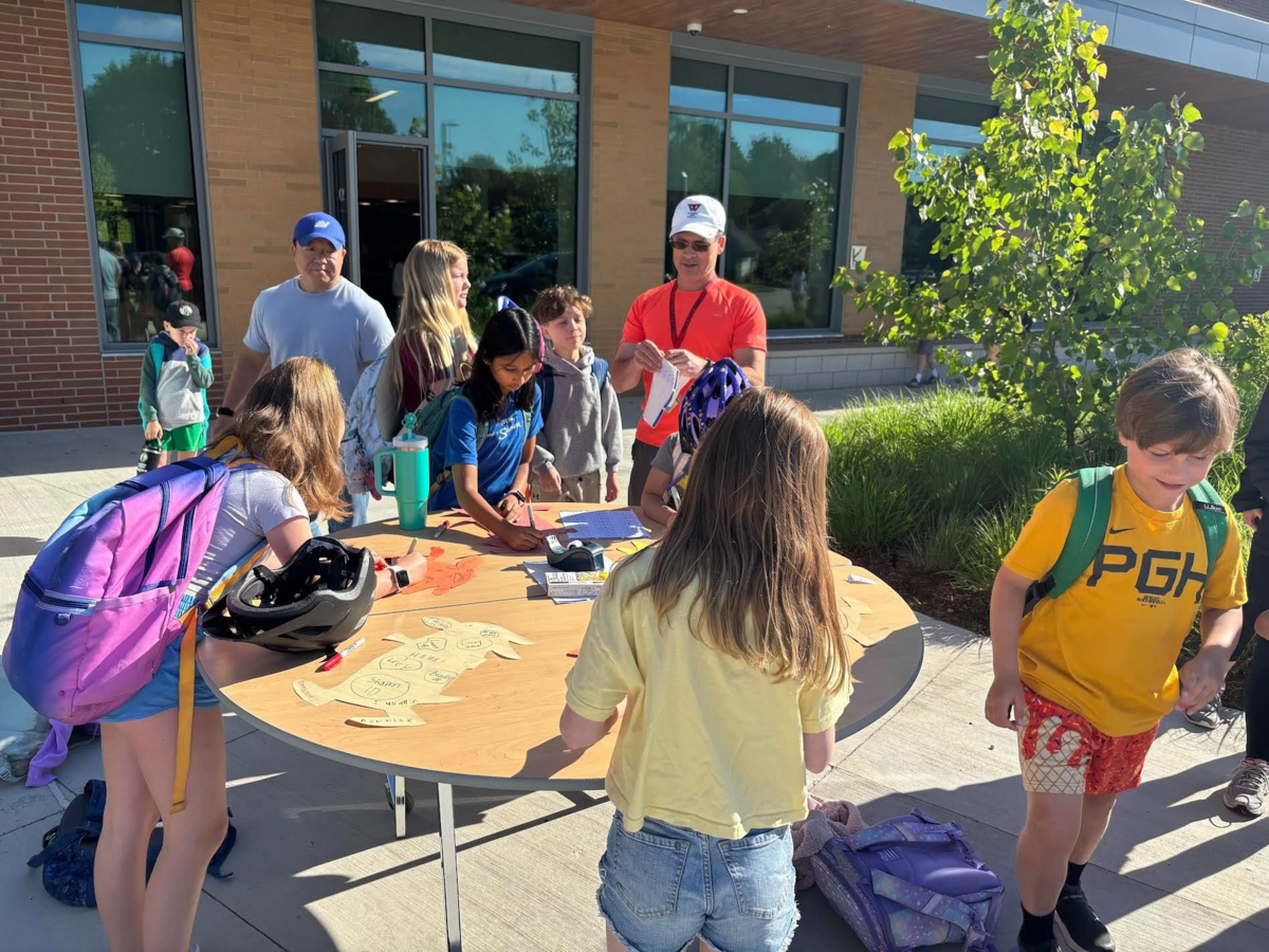 Mr. Guzzi hands out stickers to students who have walked to school.
