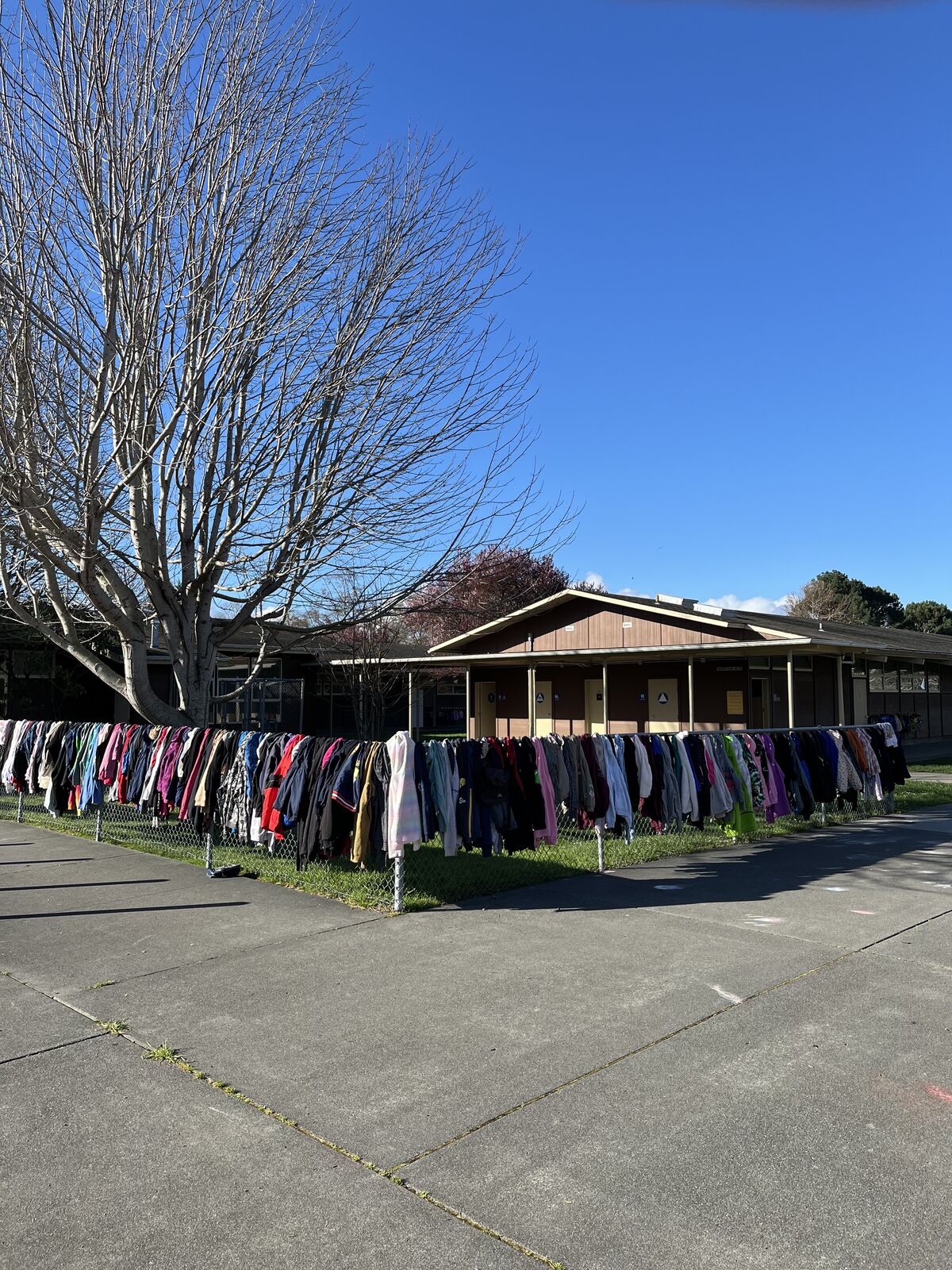A chain-link fence is adorned with a colorful display of clothing items, hung neatly in rows.