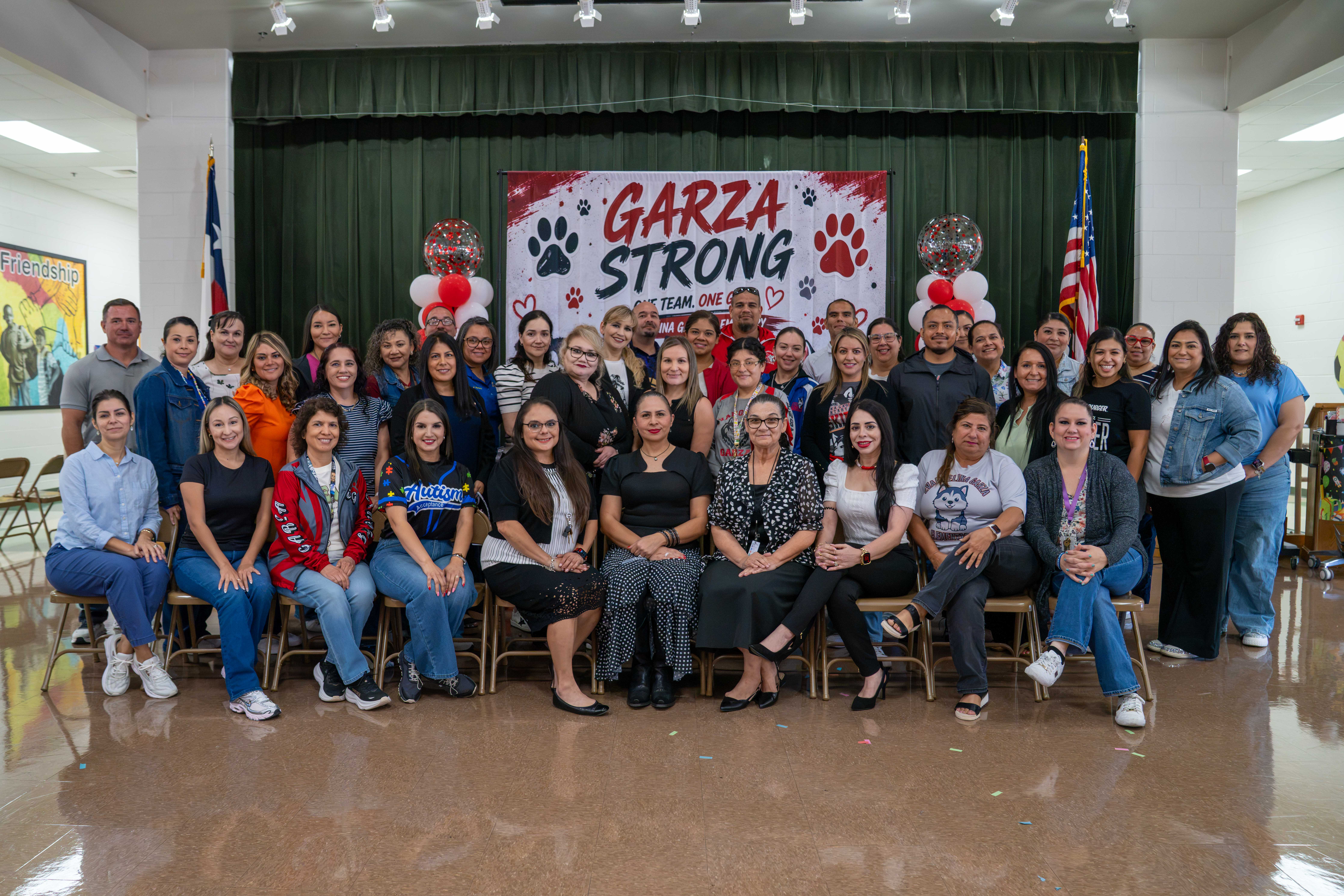 A large group of people, likely staff and students, pose for a photo in front of a banner that reads 'GARZA STRONG'.