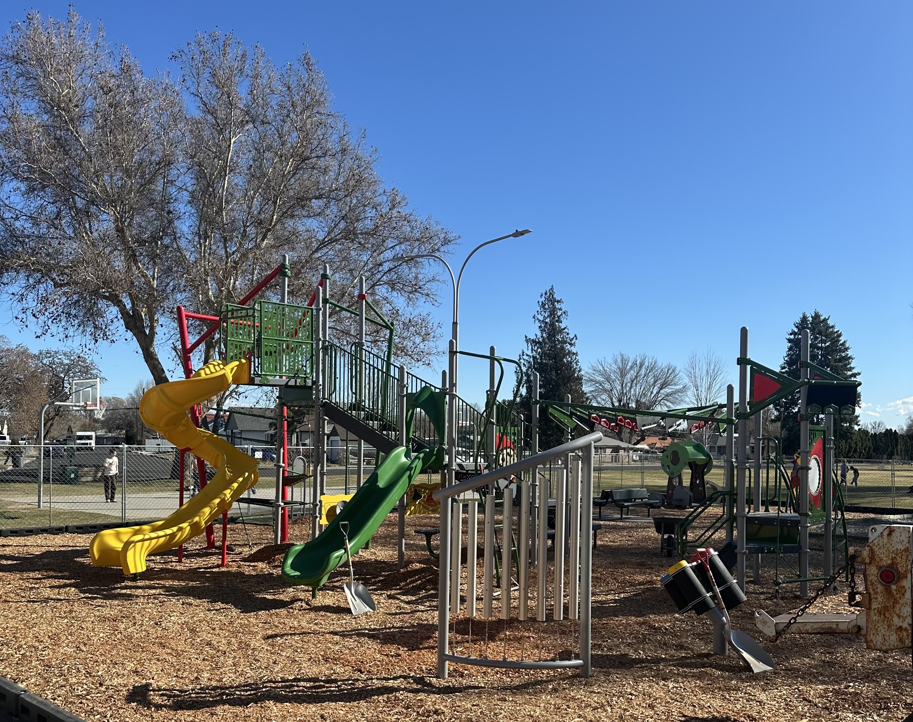 A colorful playground with slides, swings, and climbing structures under a clear blue sky.