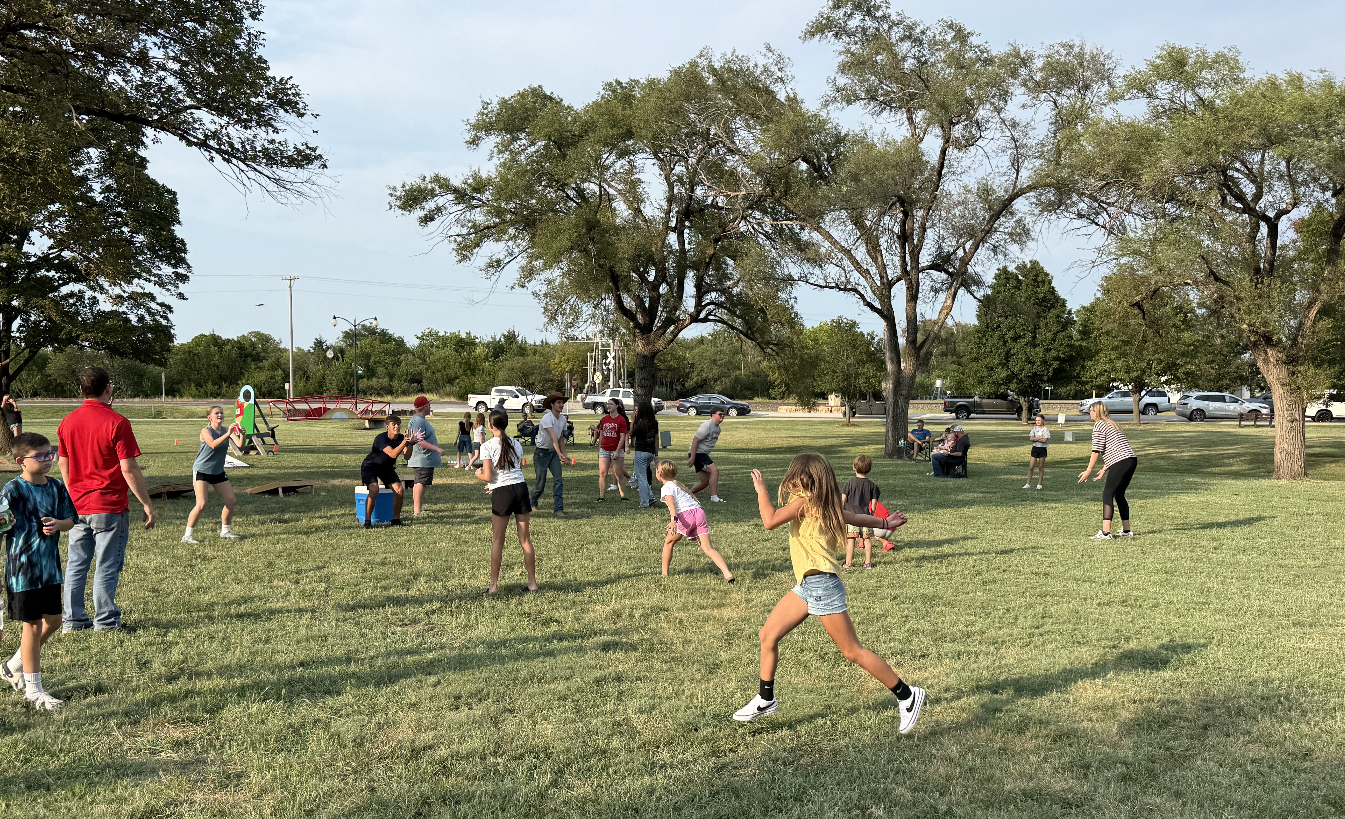 A group of people, including children and adults, are playing games on a grassy field.