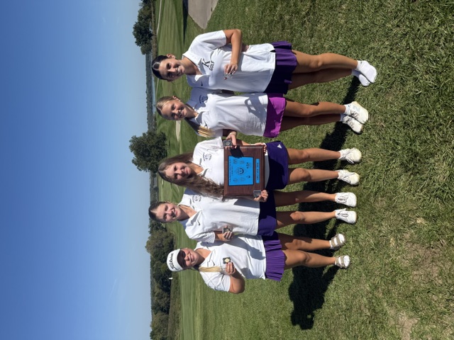 Five golfers stand on a golf course, posing for a photo with a trophy and medals.