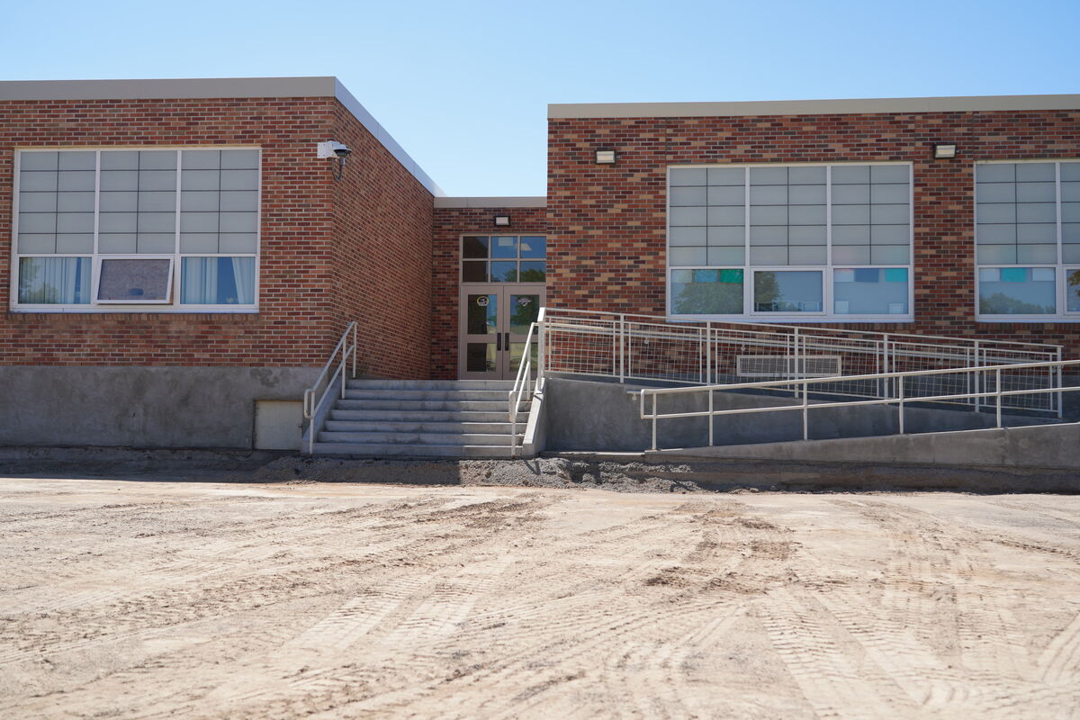 A brick building with large windows and a ramp leading to the entrance.