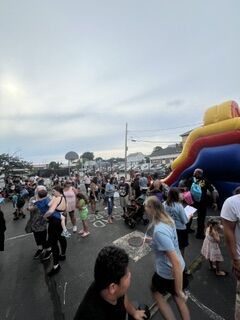 A crowd of people gathers outdoors, with a large inflatable structure in the background.