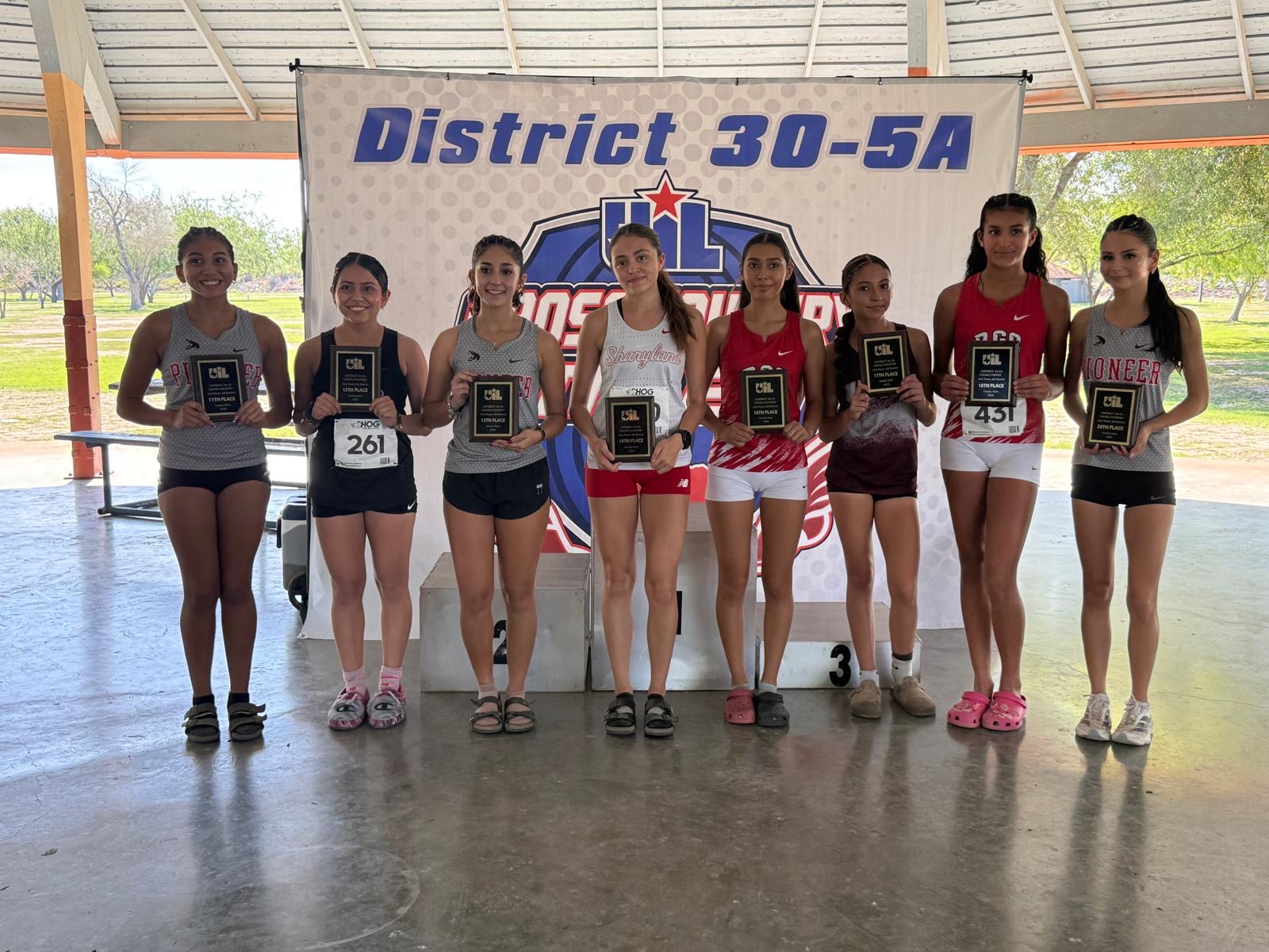 Eight high school cross country runners pose proudly with their achievement plaques in front of a District 30-5A banner.