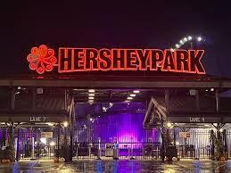 The illuminated Hersheypark sign glows brightly at night above the park entrance.