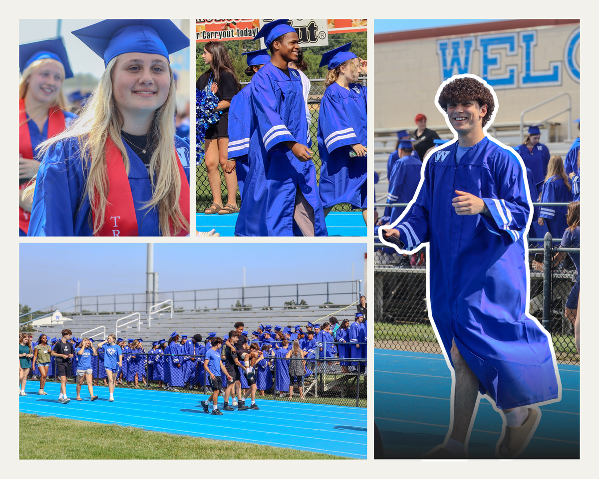 Graduates in blue gowns and caps walk on a blue track at an outdoor ceremony.