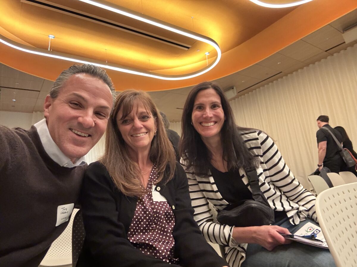 Dr. Libano, Mrs. Fratus, and Mrs. Boulet smile for a selfie under bright modern lighting indoors.