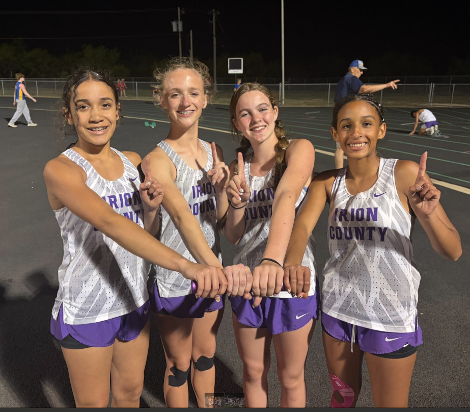 Four young female athletes in matching 'Union County' track uniforms smile and hold hands, showing off their victories.