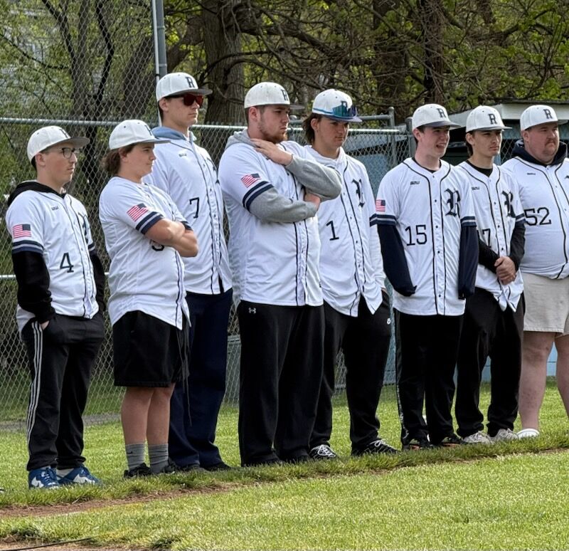 Baseball players wearing white jerseys with 'R' logos and black pants stand at attention.