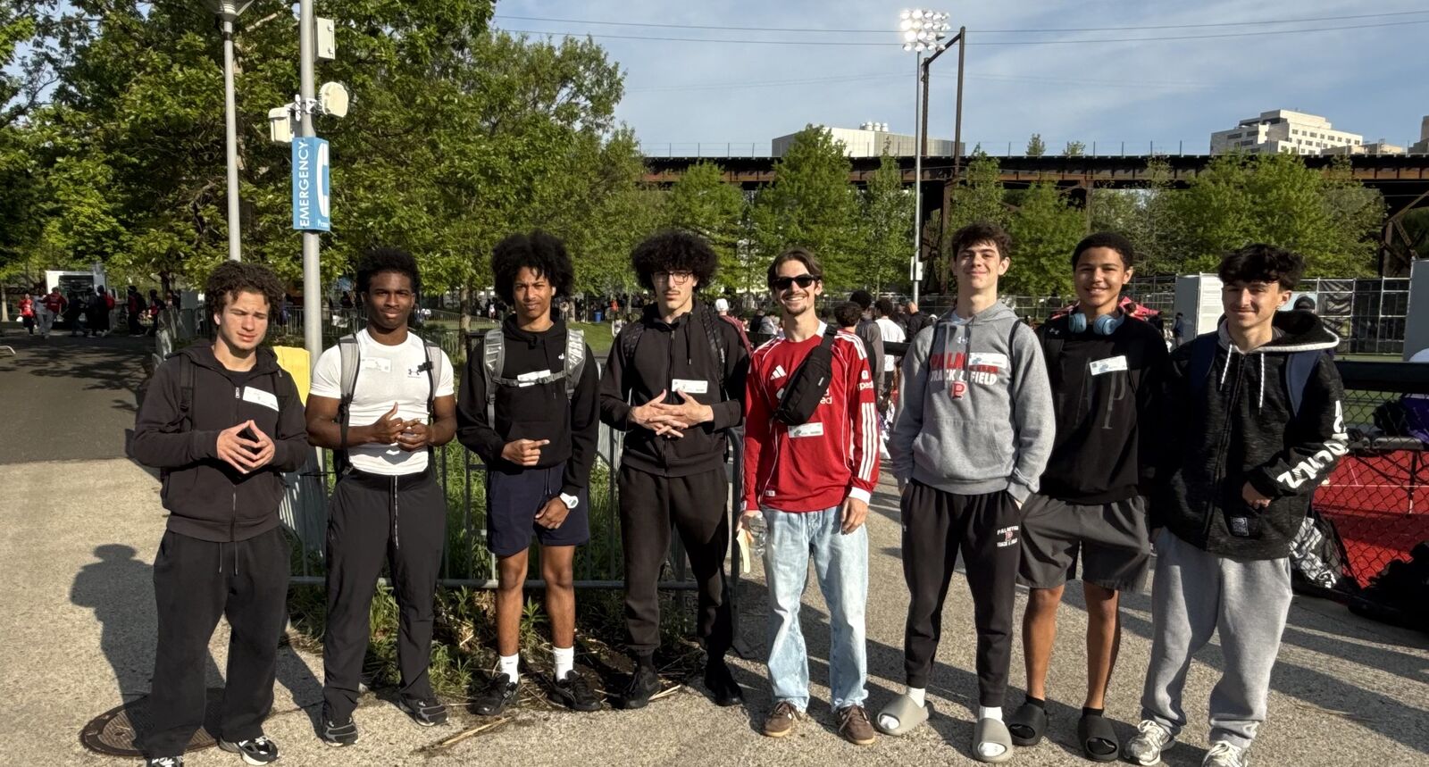 A group of seven young men stand together outdoors, posing for a photo.