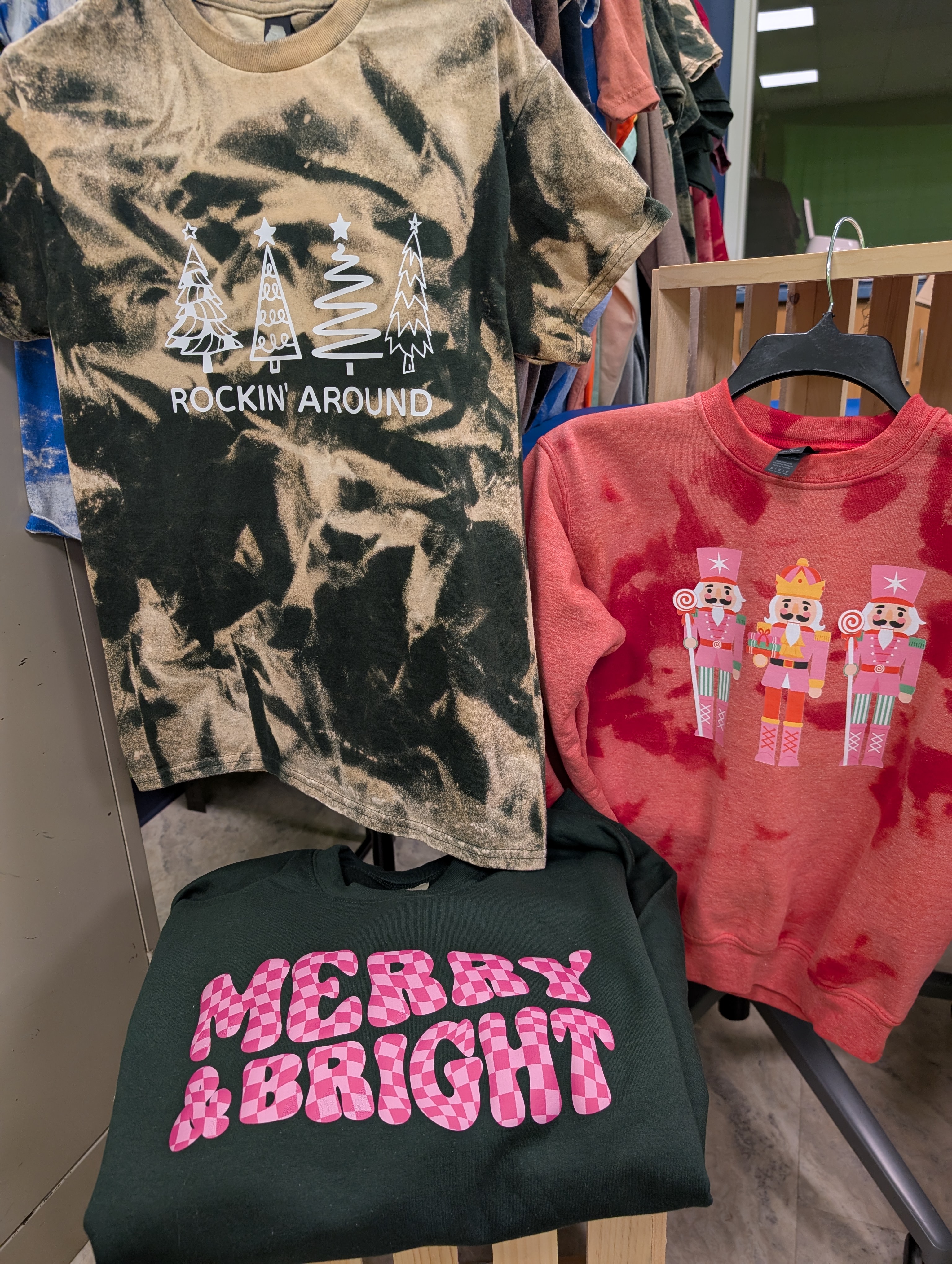 A dark green sweatshirt with pink checkered text that reads 'MERRY & BRIGHT'.