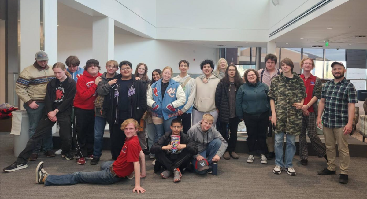 A diverse group of young people and an adult stand together in a modern indoor space.