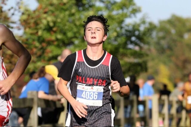 A young runner wearing a Palmyra track uniform and bib number 4036 competes in a cross-country race.