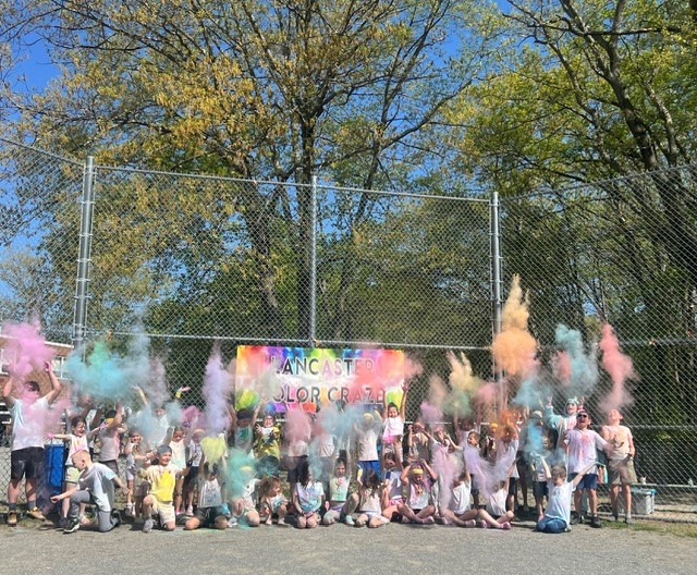 Children joyfully throw colorful powder in the air at the Lancaster Color Craze event.