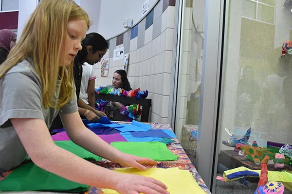 Davis students working on their collective canvas project at a table in the hallway.